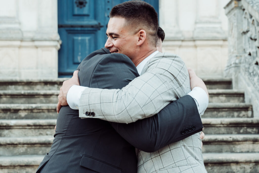 Two men wearing suits sharing a warm embrace.