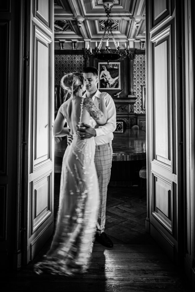 Black and white image of the bride and groom sharing a hug in the entrance to a room.