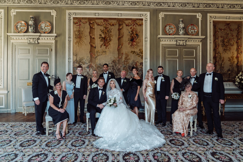 Traditional wedding photo of a small wedding party in an ornate room.
