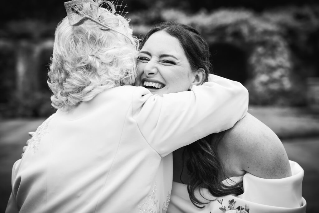 A smiling Bride is embraced by a wedding guest,