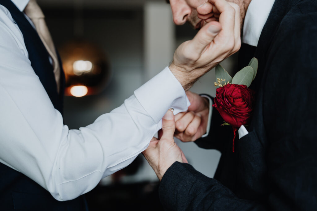 Close-up of a groomsman helping the groom fasten his cufflinks.