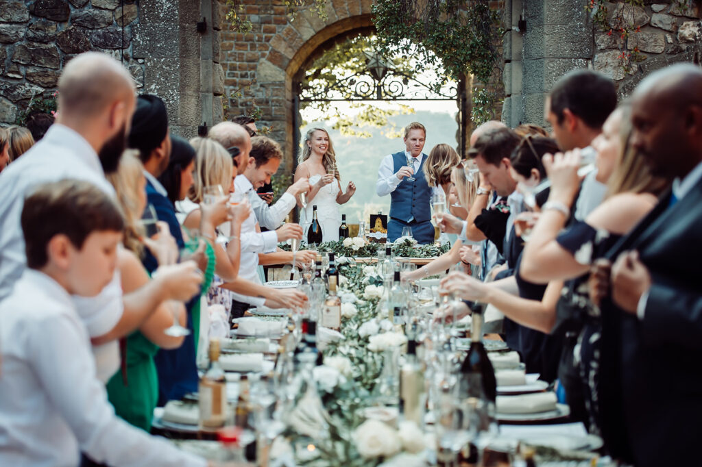 Bride, Groom and Wedding Guests standing around the table at an outdoor wedding reception.