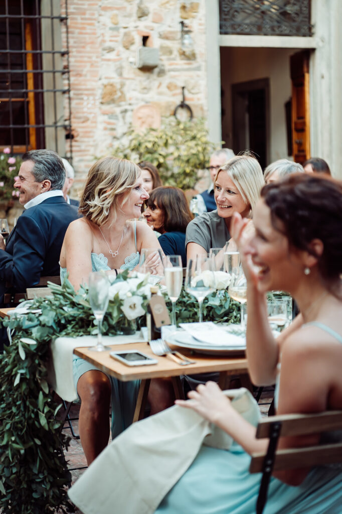 Smiling wedding guests sat at outdoor dining tables