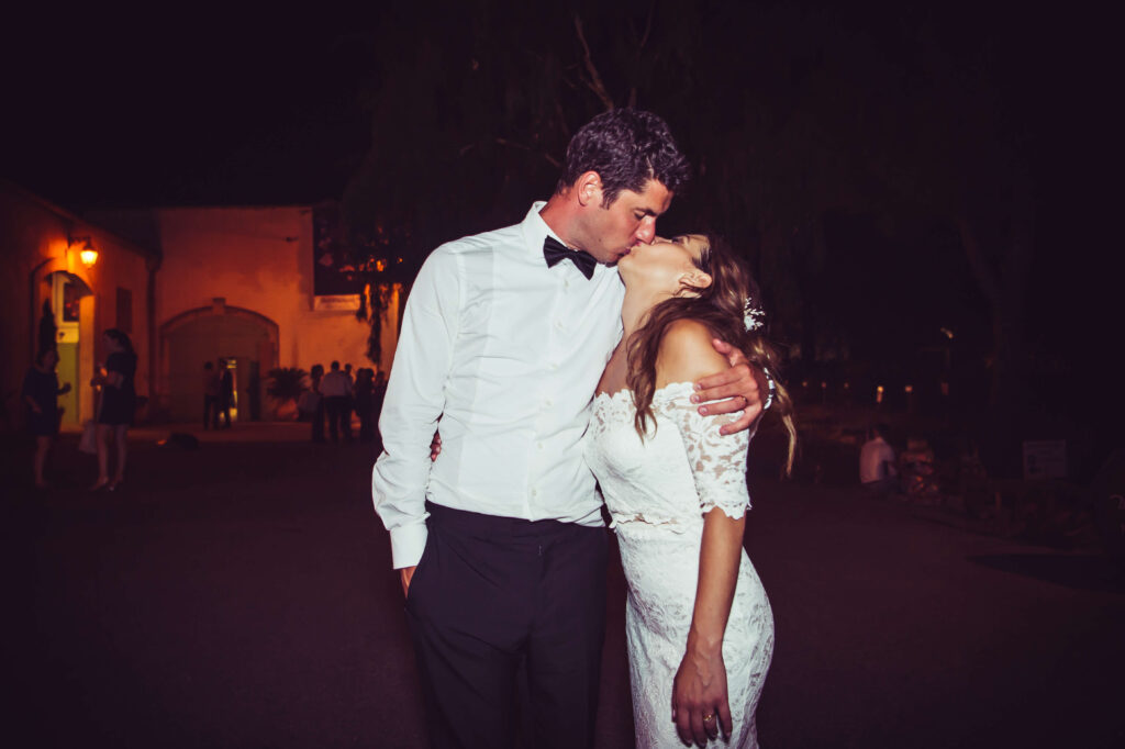 Bridegroom holding his Bride around her shoulders and kissing her.