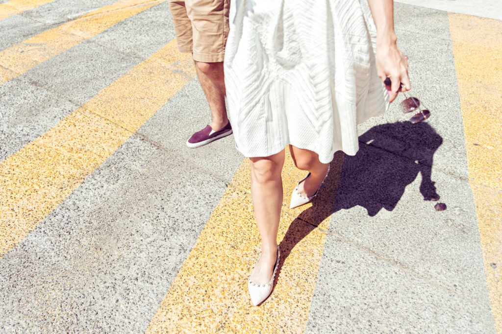 Legs of a Bride and Groom as they walk along a yellow-striped road.