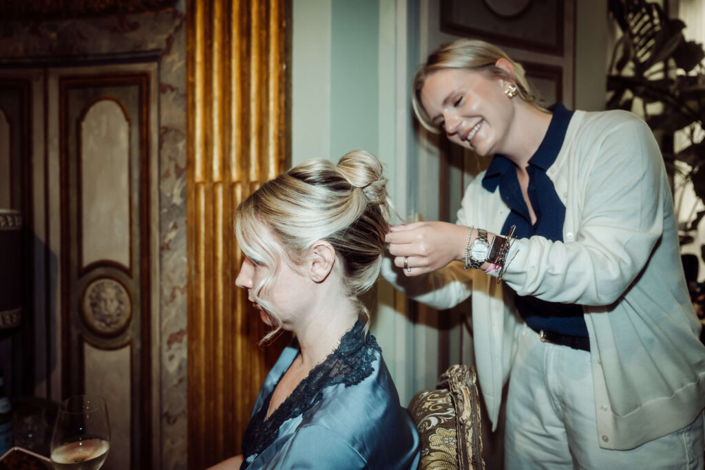 Side profile of Bride, in dressing gown, having her hair styled.