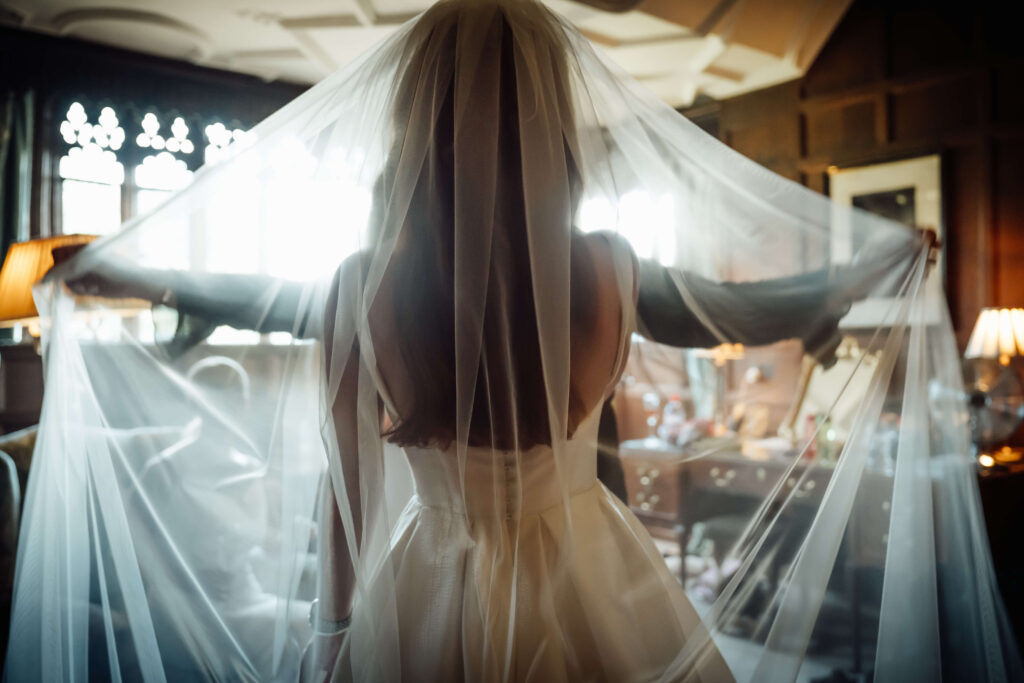 Bride photographed from behind, showcasing the back of her wedding dress and veil.
