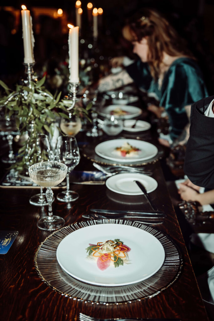 Elegant wedding reception table set with plated food, glassware, and floral styling.