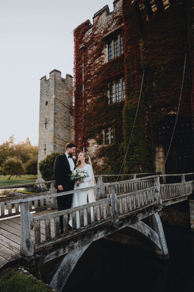 Wedding couple standing together on the bridge in front of Hever Castle.