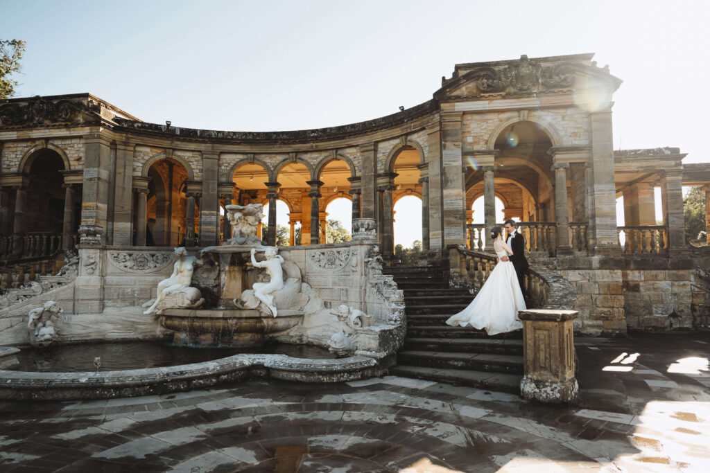 Bride standing on the steps of a grand fountain terrace at a stately wedding venue.