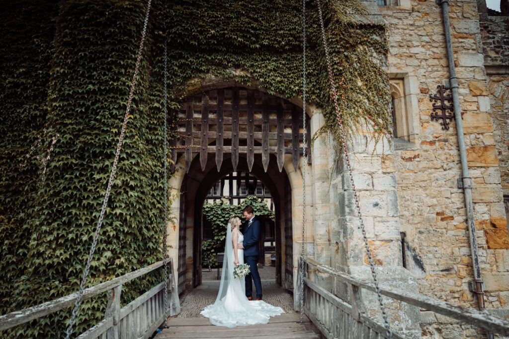 Wedding couple standing together under the archway of a castle entrance on a drawbridge