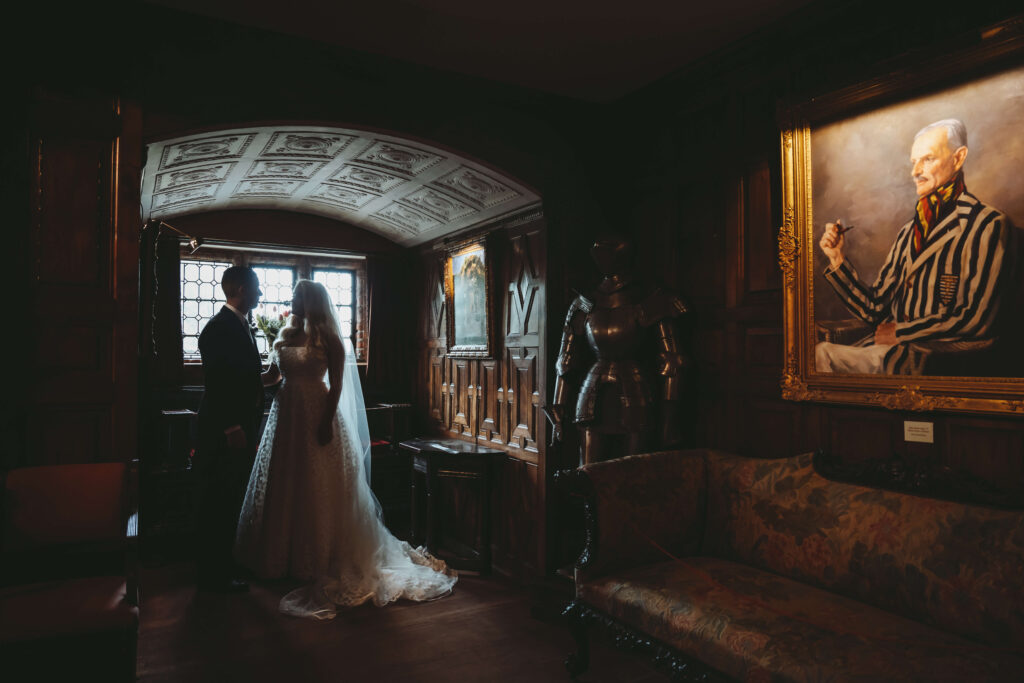 Wedding couple looking at each other in a dimly lit historical room.