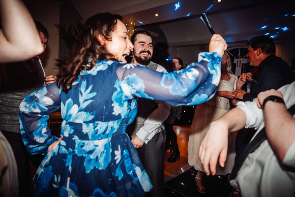 Wedding guests dancing together and laughing.