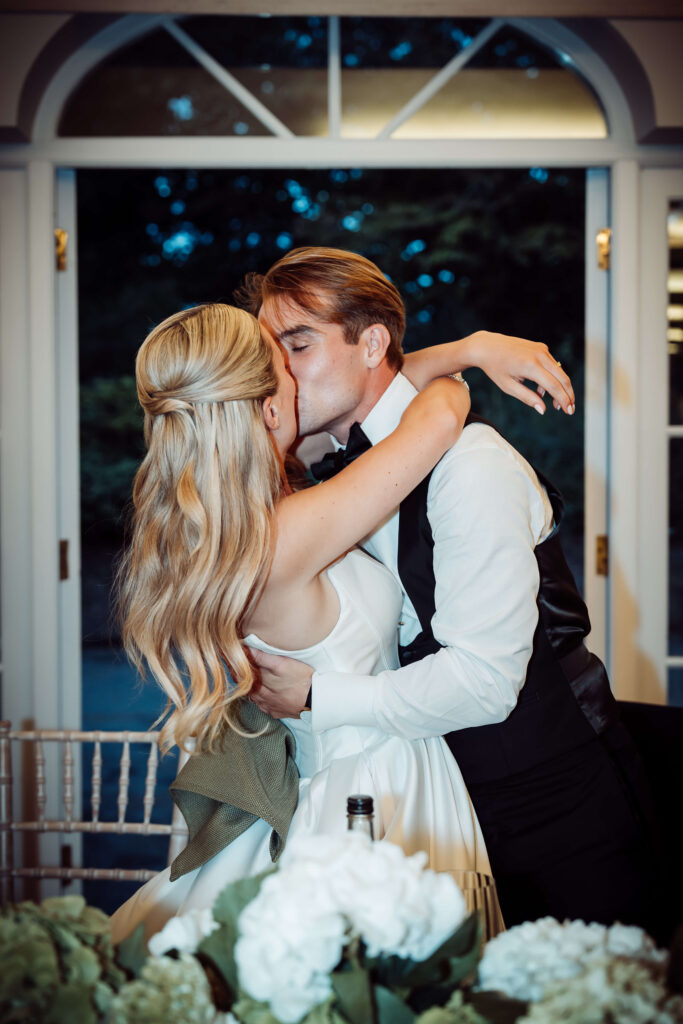 Wedding couple kissing and embracing indoors in a doorway at their reception.