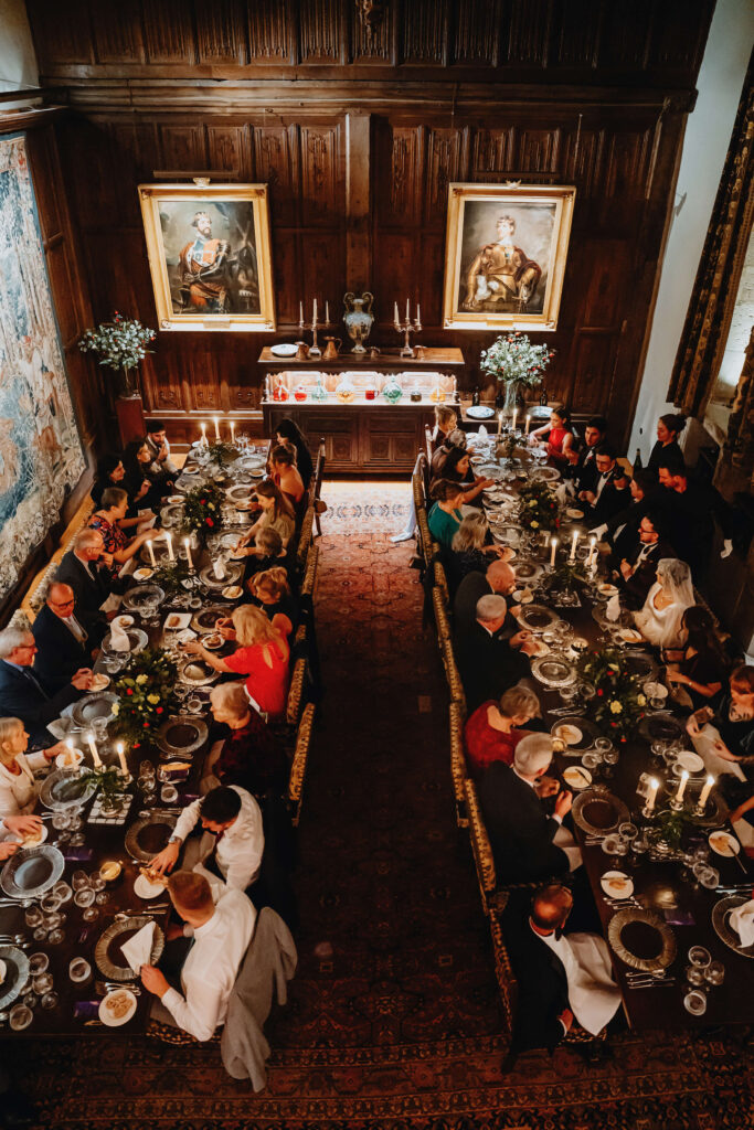 High-angle view of a wedding reception in a dimly lit historic room.