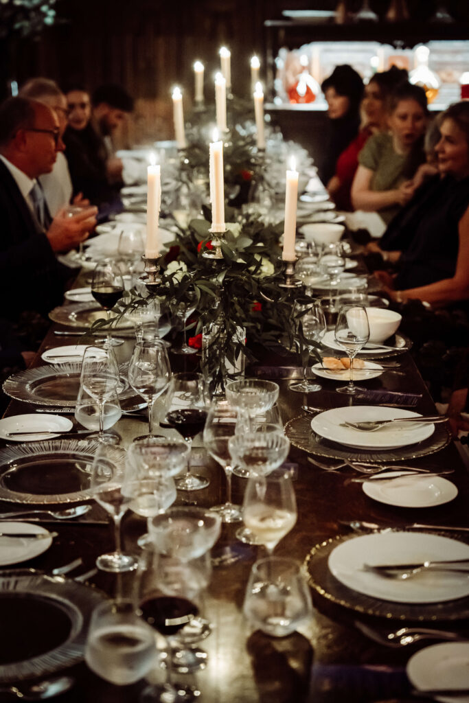 Wedding reception table set with candles, flowers, and guests seated ready for the celebration.