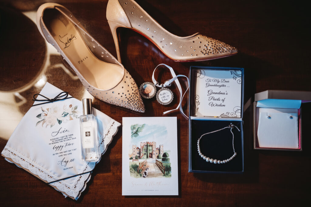 Elegant bridal accessories including Louboutin heels, perfume, and a pearl necklace, captured by Luxury Wedding Photographer in Kent, Teri V Photography.