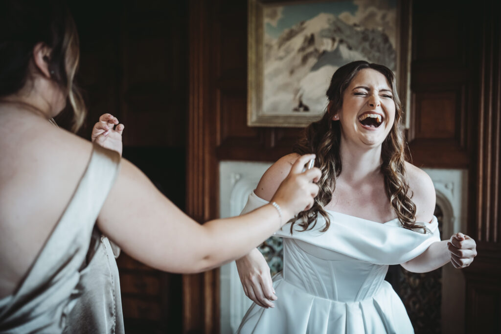 Bride laughing joyfully with bridesmaid.