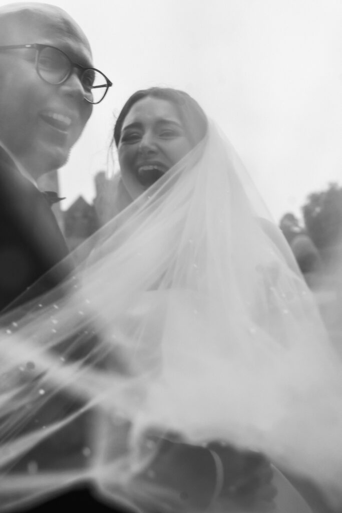 Bride and groom laughing joyfully under the veil, captured by Luxury Wedding Photographer in Kent, Teri V Photography.