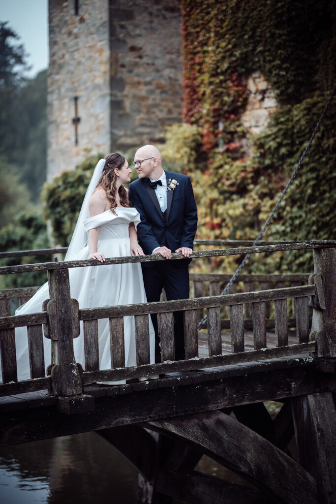 Bride and groom sharing a tender moment on a wooden bridge at Hever Castle, captured by Luxury Wedding Photographer in Kent, Teri V Photography.