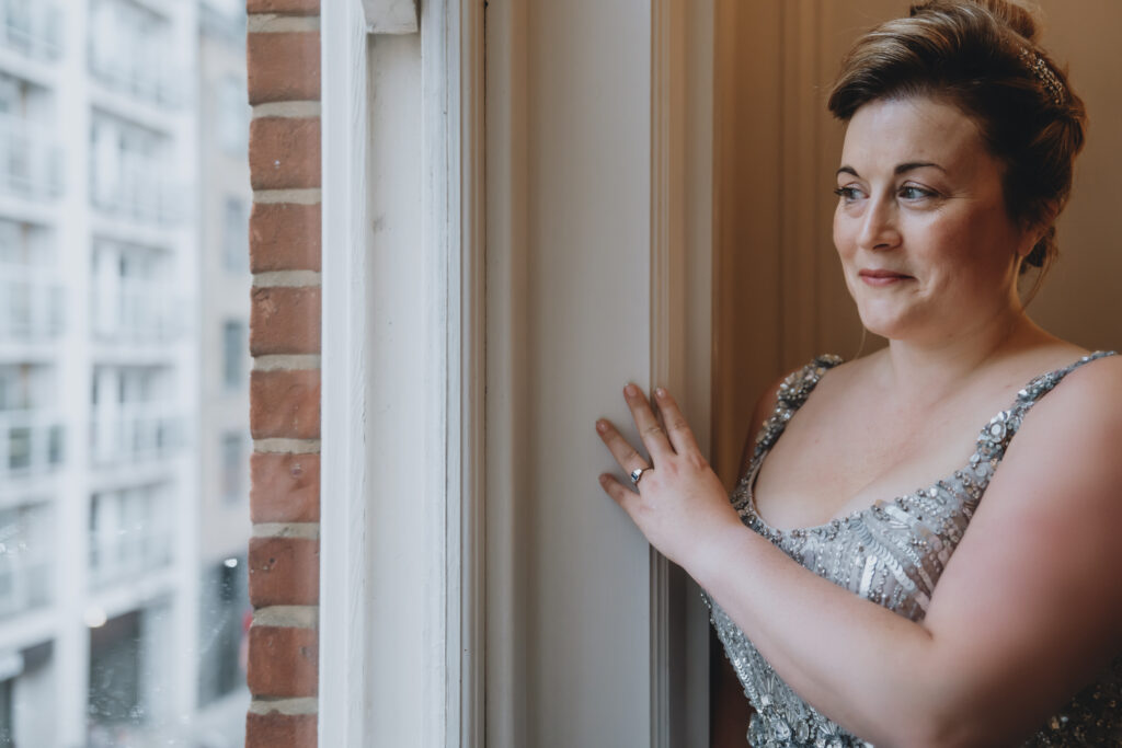 Bride standing by a window with a smile at The Swan London venue.