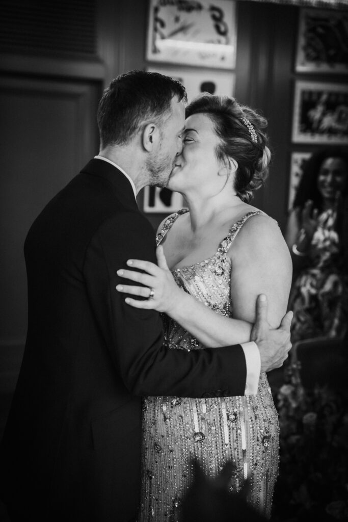 Black and white photo. Bride and groom sharing a kiss during their Swan London wedding ceremony. Captured by wedding photographer