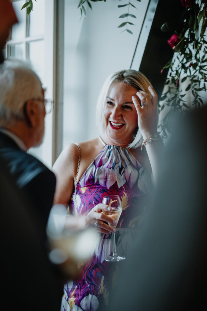 Candid moment of guest smiling and chatting at a Swan London wedding reception. 