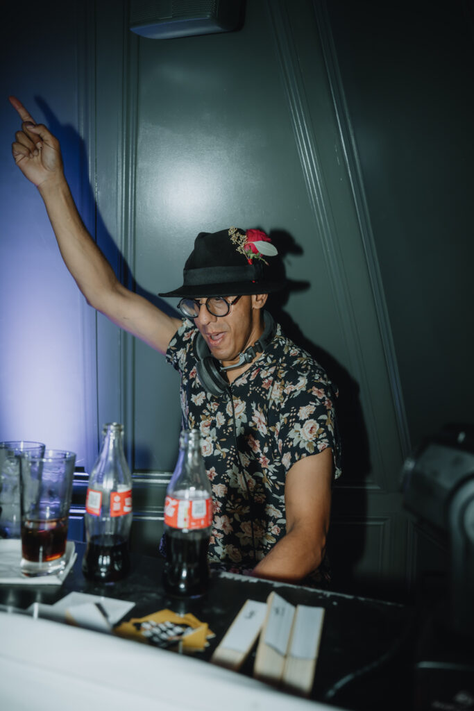 candid shot of DJ performing with arm raised at a wedding celebration in Swan London.