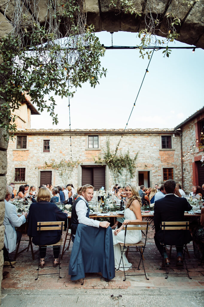Bride and groom turning to the camera during the reception, framed by a stone archway