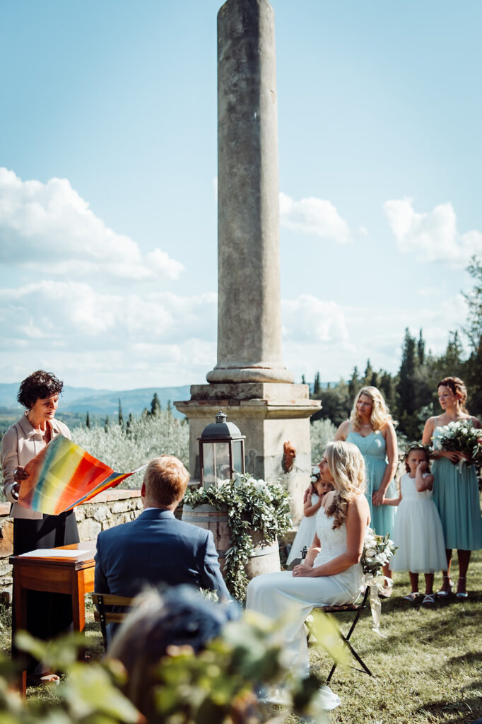 Bride and groom sitting at the front of the ceremony with sweeping Chianti hills in the background