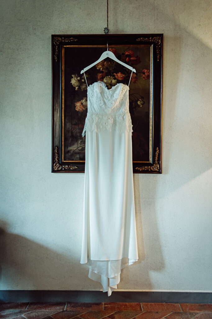 Wedding dress on a hanger resting on a framed painting