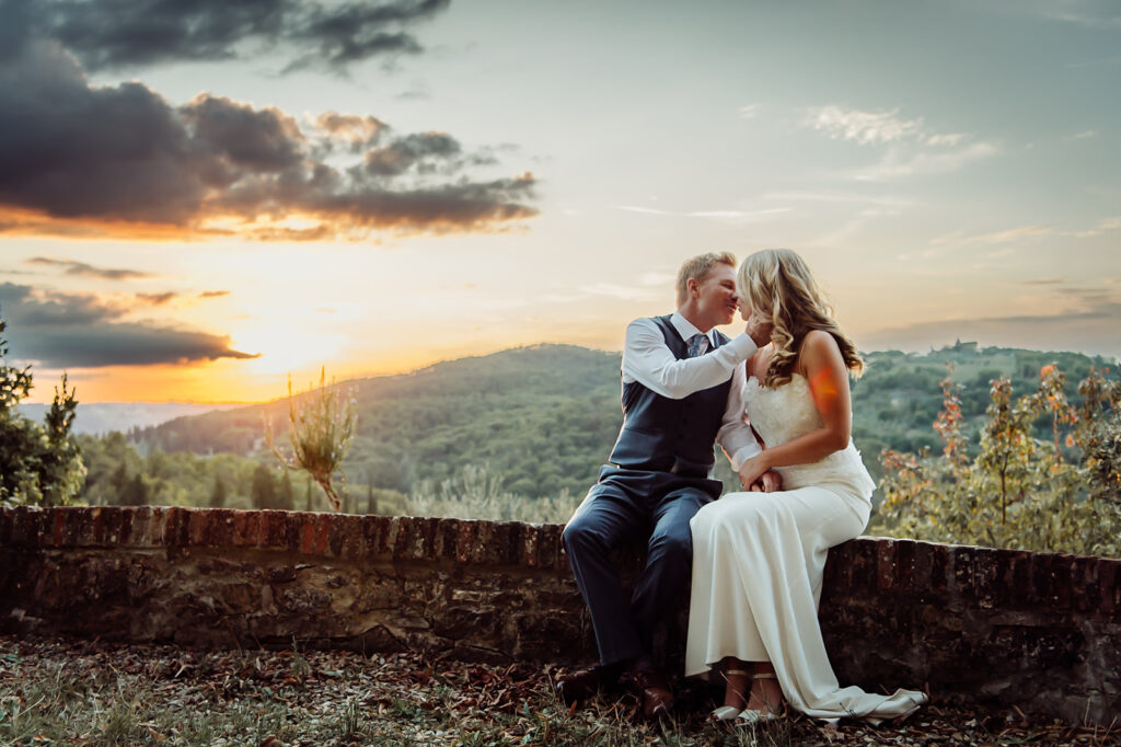 Couple kissing at golden hour with rolling hills in the background during their Tuscan wedding celebration.