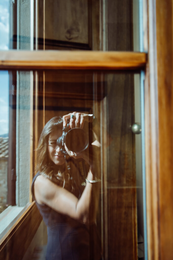 Luxury destination wedding photographer Teri V capturing a self-portrait through a reflective surface during a wedding in Italy.