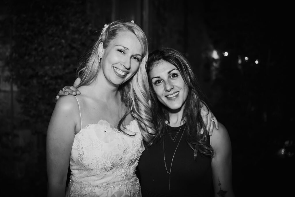 Black and white photo of Castello di Cafaggio Wedding Photographer Teri Vincent embracing bride Adele and smiling at the camera.