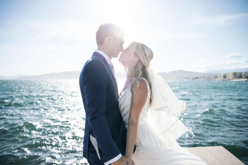 Couple kissing with the sea in the background and sun rays shining between them.