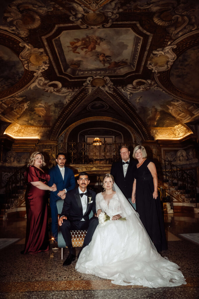 An indoor formal shot of small wedding party with golden architecture in the background. [Teri V Photography Wedding Timeline Guide]