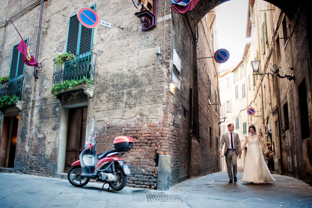 Wide shot of a couple walking through a charming town street during a European destination wedding photoshoot