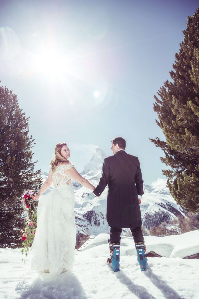 Bride and groom holding hands with a snowy mountain behind them during a European destination wedding
