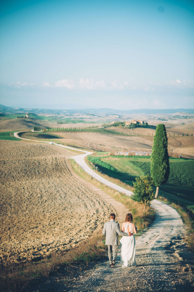 Shot of the couple walking together down a long windy path, showing the view in the background.