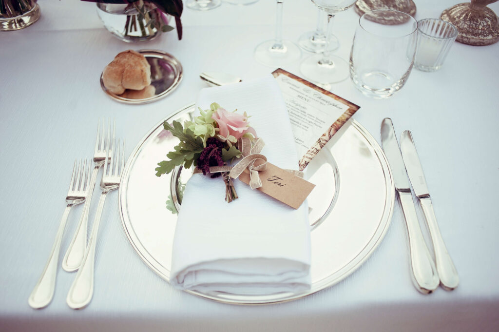 In a destination wedding, place setting with name card ‘Teri’, elegant table styling with plate, cutlery, and napkin