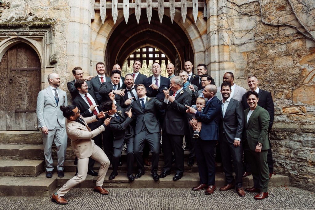 Group shot of men from a wedding party pointing and smiling at the Groom.