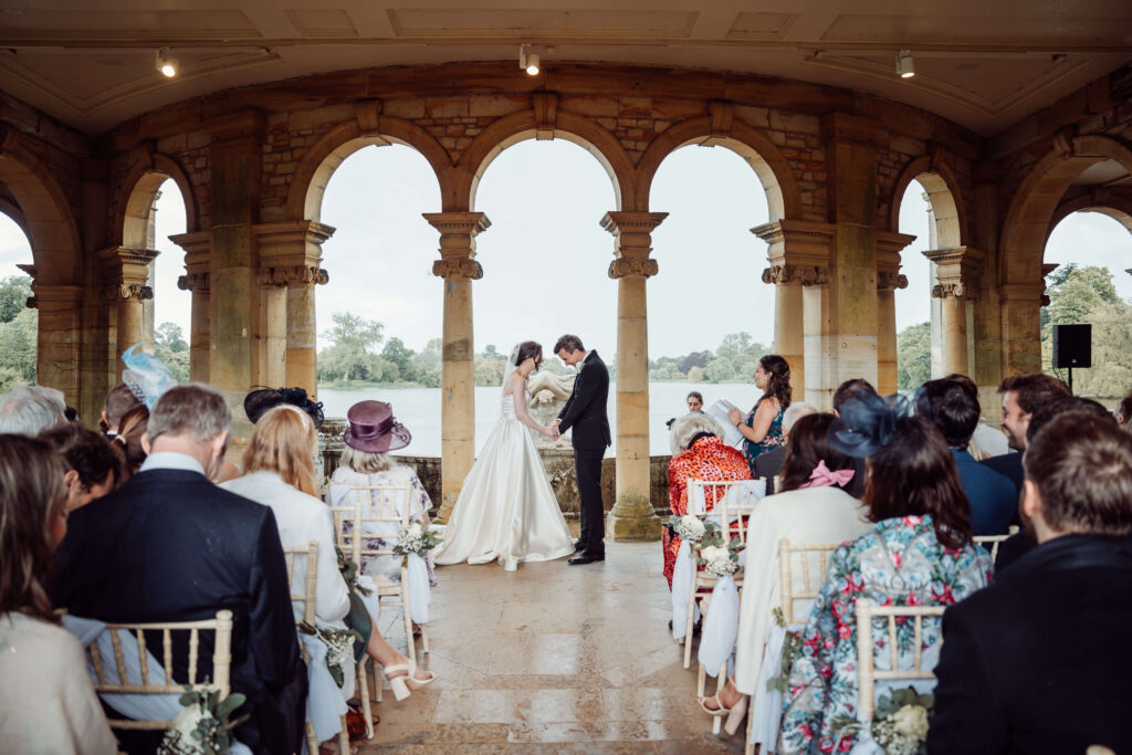 Ceremony picture from the isle, with couple holding hands. The wedding guests sit in front of them.