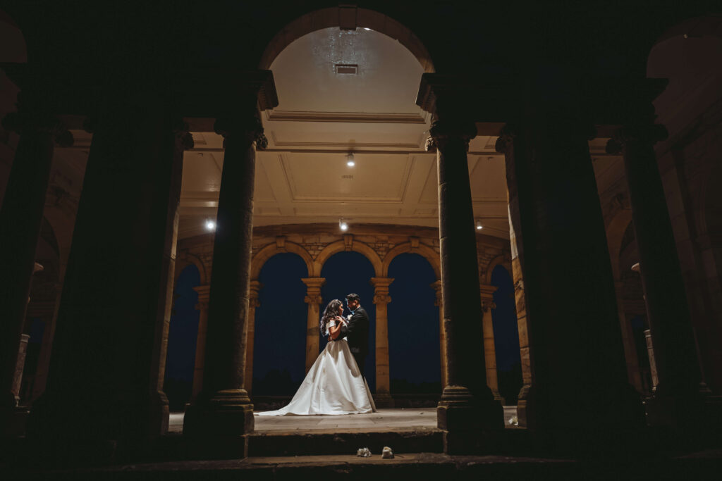 Wide shot of wedding couple embracing in the Loggia, at Hever Castle. This shot was taken in the evening 