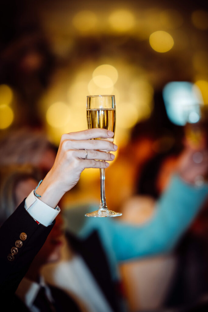 Close up shot of someone holding up a flute. it is focused on the drink with the backdown blurred