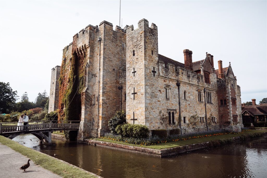 Wide shot of Hever Castle with a couple kissing on the bridge,