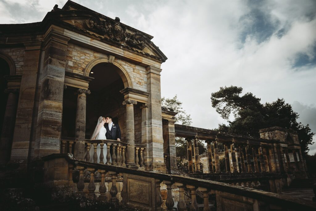Wedding couple kissing on a balcony in the Loggia at Hever Castle